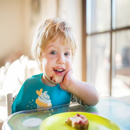 A cute toddler boy eating at home.